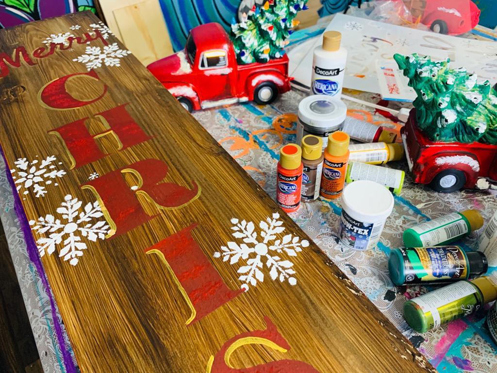 Merry christmas porch sign next to acrylic paints